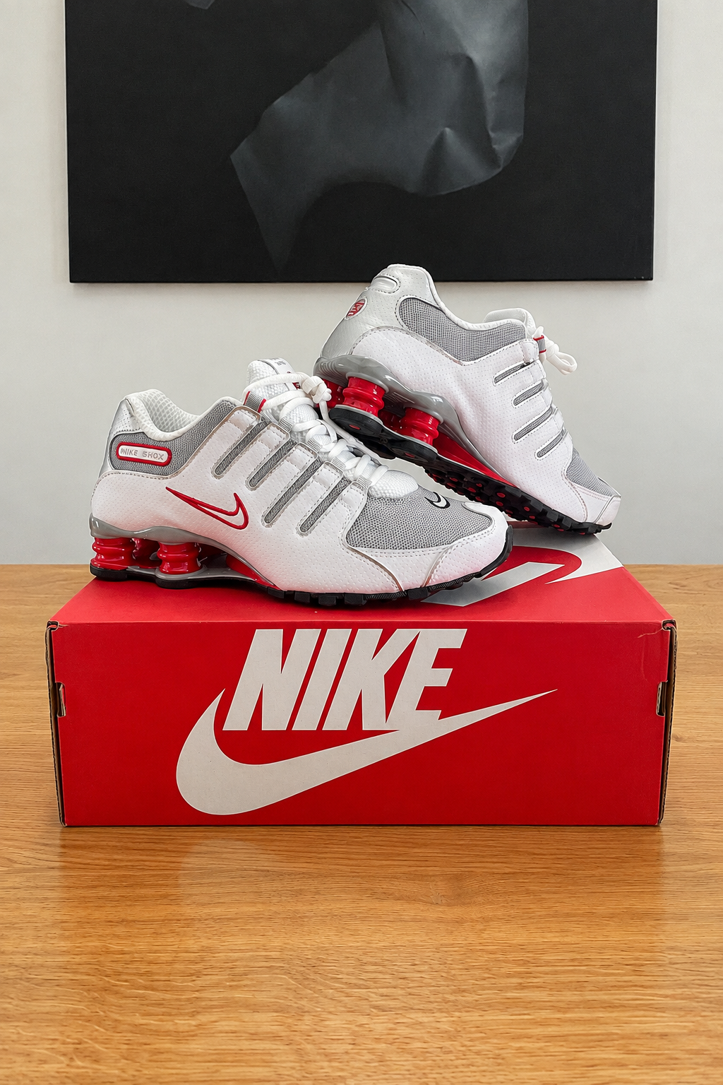 Version retouchée générée de la première photo des Nike Shox NZ : boîte rouge NIKE centrée sous le tableau noir