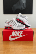 Version retouchée générée de la première photo des Nike Shox NZ : boîte rouge NIKE centrée sous le tableau noir