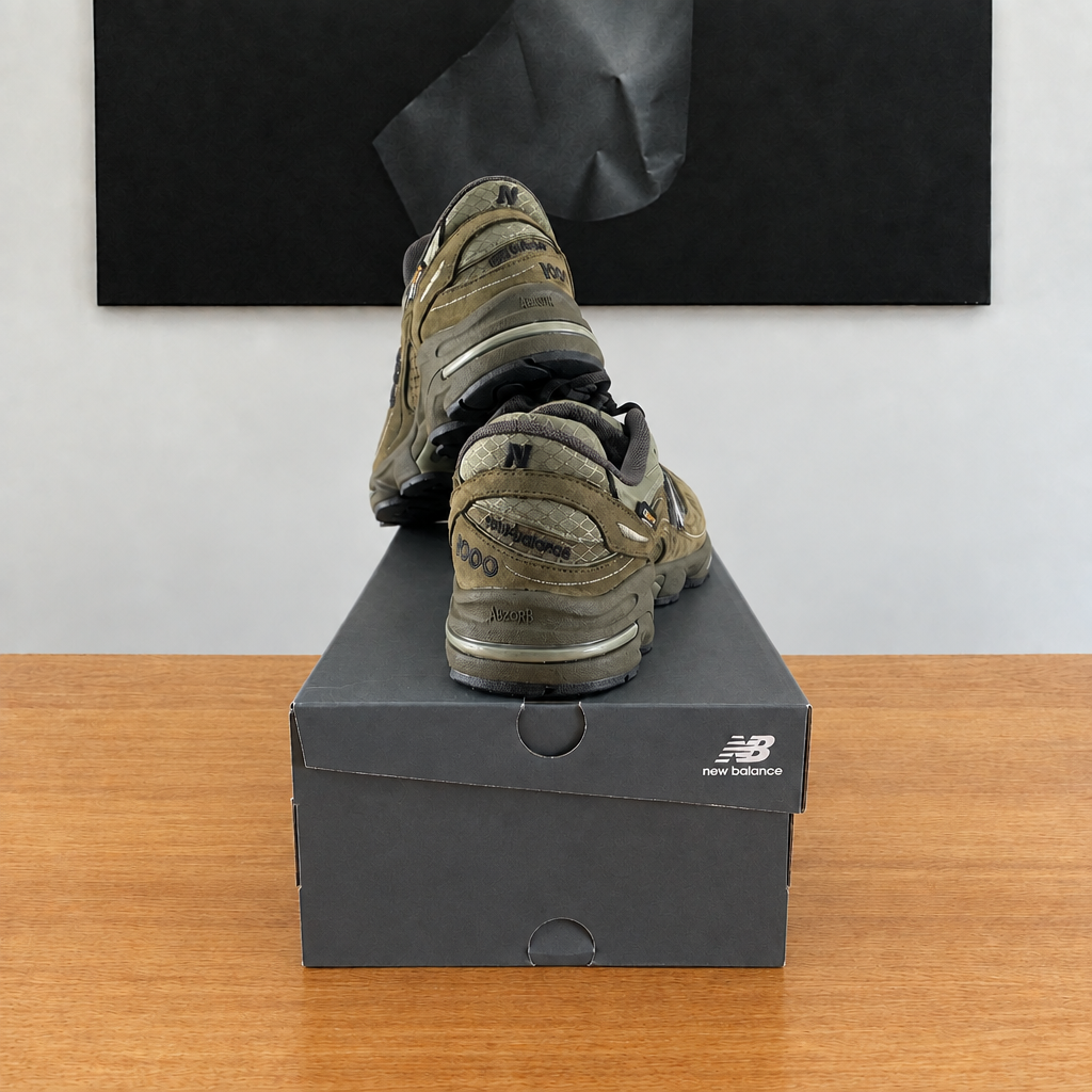 New Balance M1000 NBU : boîte et chaussures centrées sous le tableau noir, sans étiquette blanche