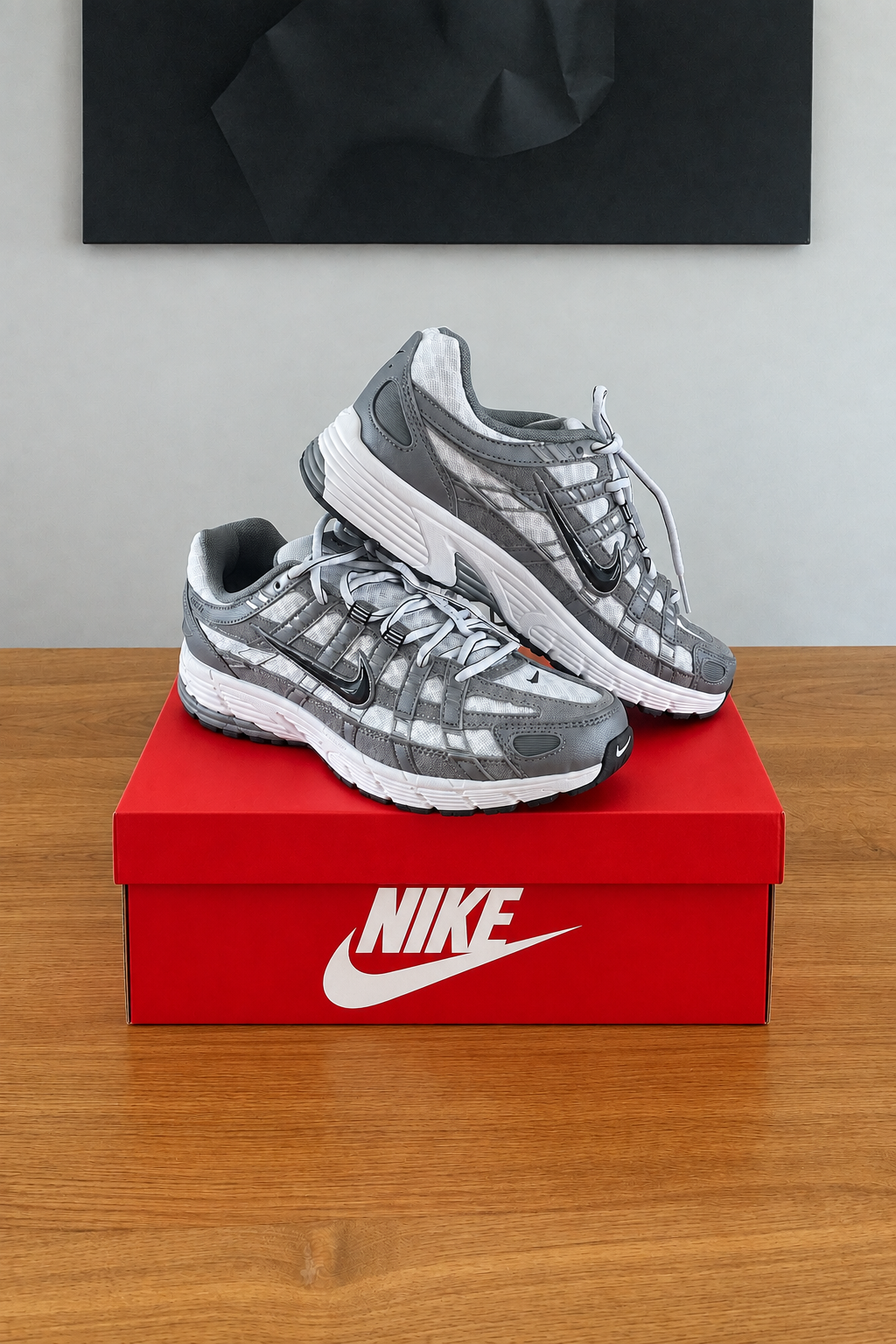 Version retouchée générée de la première photo, boîte NIKE rouge et chaussures recentrées sous le tableau noir