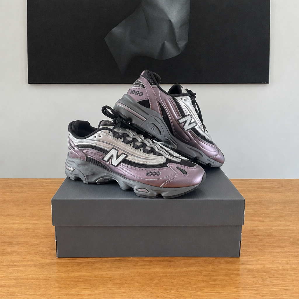 New Balance M1000 EGY : boîte et chaussures centrées sous le tableau noir