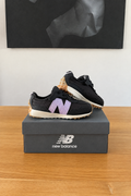 New Balance NW327WG de profil sur boîte recentrée avec logo