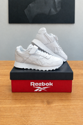 Version retouchée générée de la première vue, marquage Reebok stylisé sur la boîte, centrée sous le tableau noir