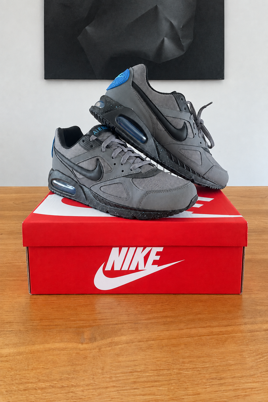 Version retouchée générée de la première vue des Nike Air Max IVO, boîte rouge NIKE centrée sous le tableau noir