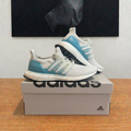 Adidas Ultraboost 1.0 blanches et turquoise sur boîte grise centrée, photo retouchée