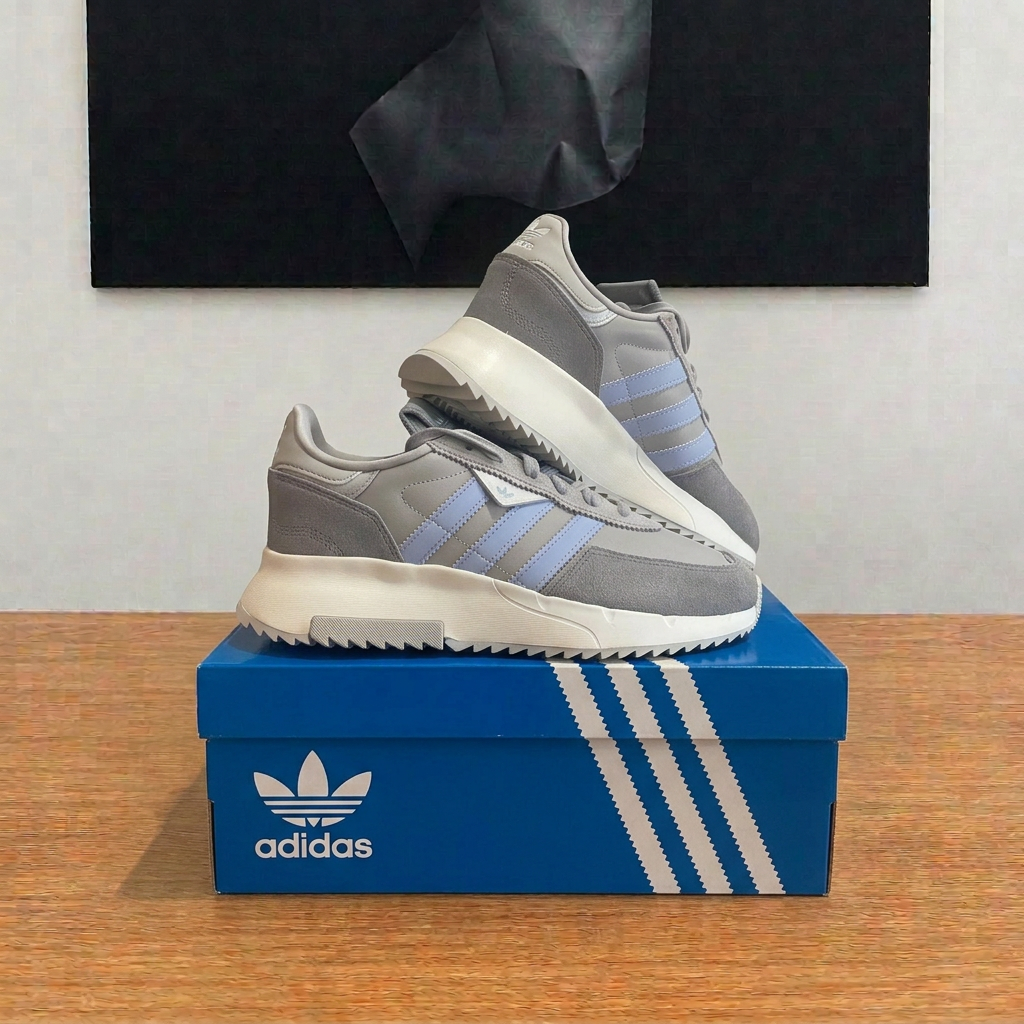 Adidas Retropy F2 W grises et bleu clair sur boîte centrée sous tableau, photo retouchée