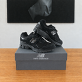 New Balance U2002 : boîte et chaussures centrées sous le tableau noir, avec logo New Balance, boîte réparée en bas à droite
