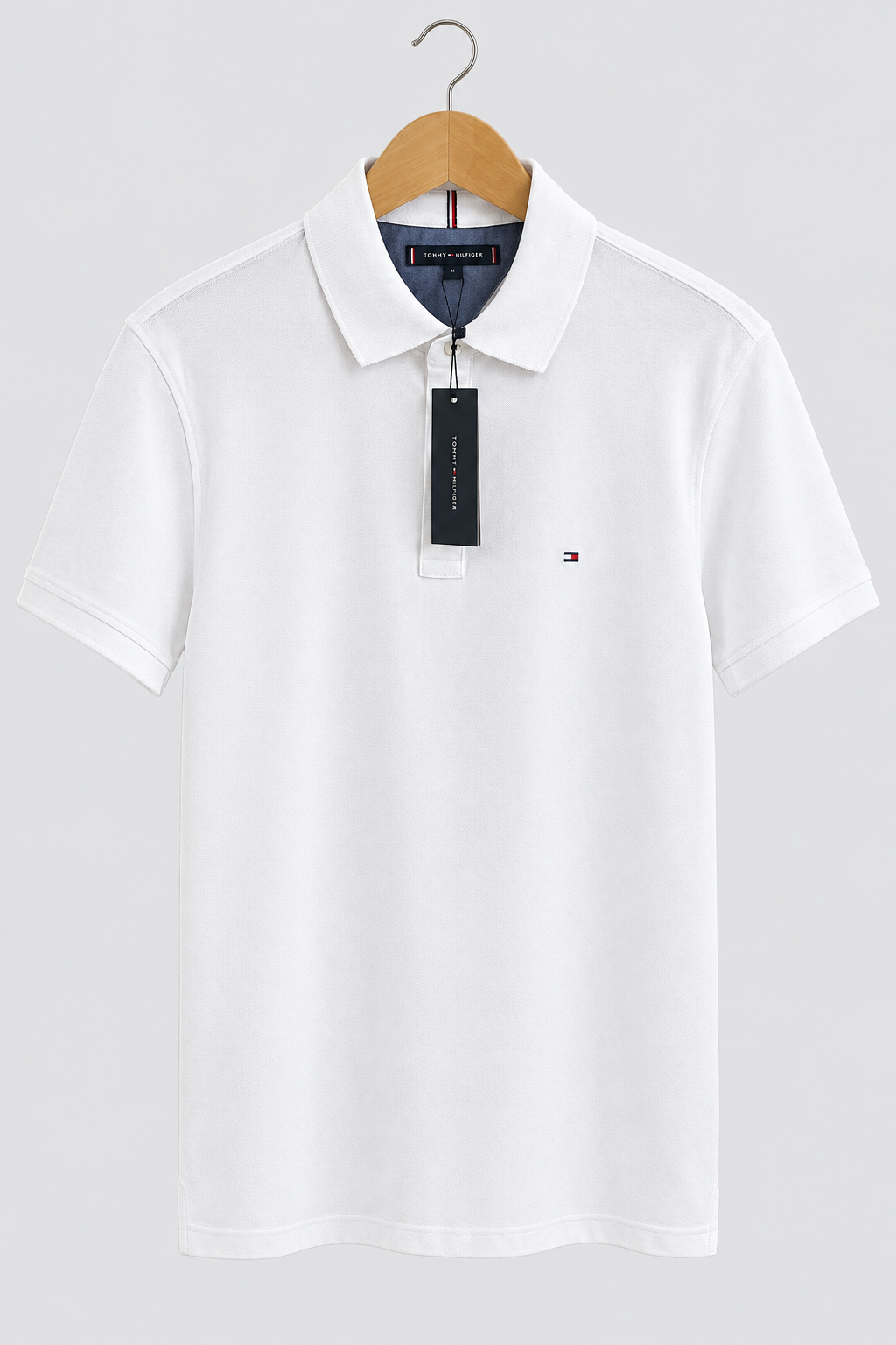 Polo Tommy Hilfiger blanc de face avec étiquette sur fond clair