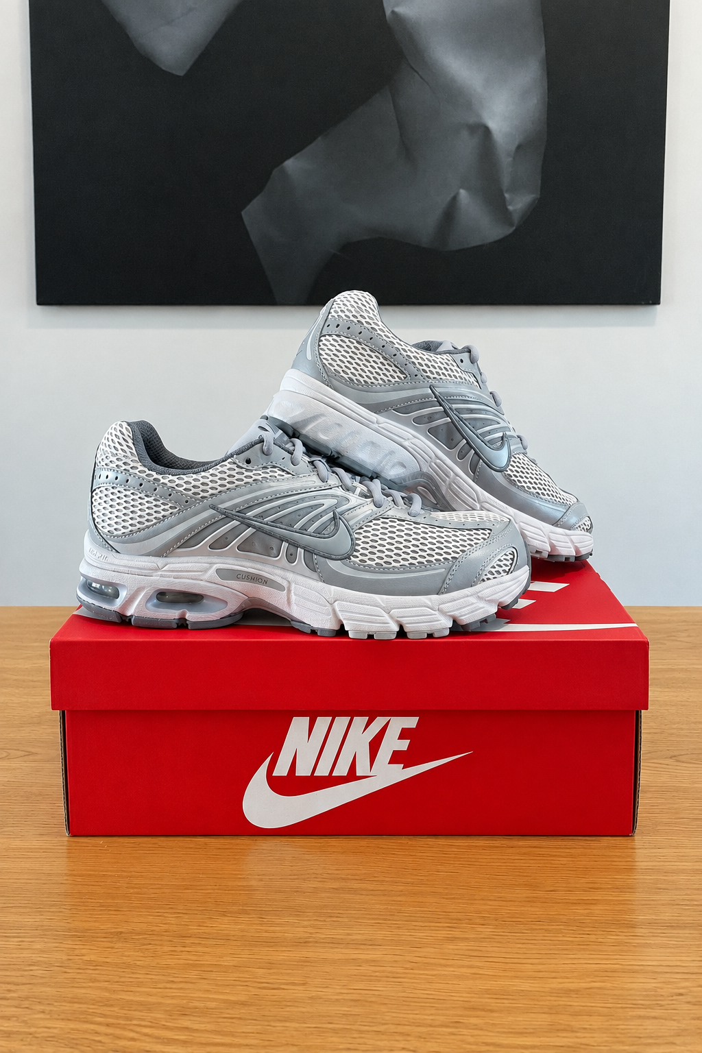 Nike Air Max Moto 2K de profil sur boîte rouge recentrée, tableau en arrière-plan