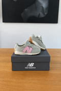 New Balance NW327WT de profil sur boîte recentrée avec logo