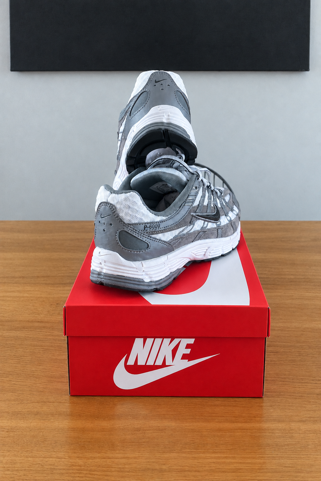 Version retouchée générée de la deuxième photo, boîte NIKE rouge et chaussures recentrées sous le tableau noir