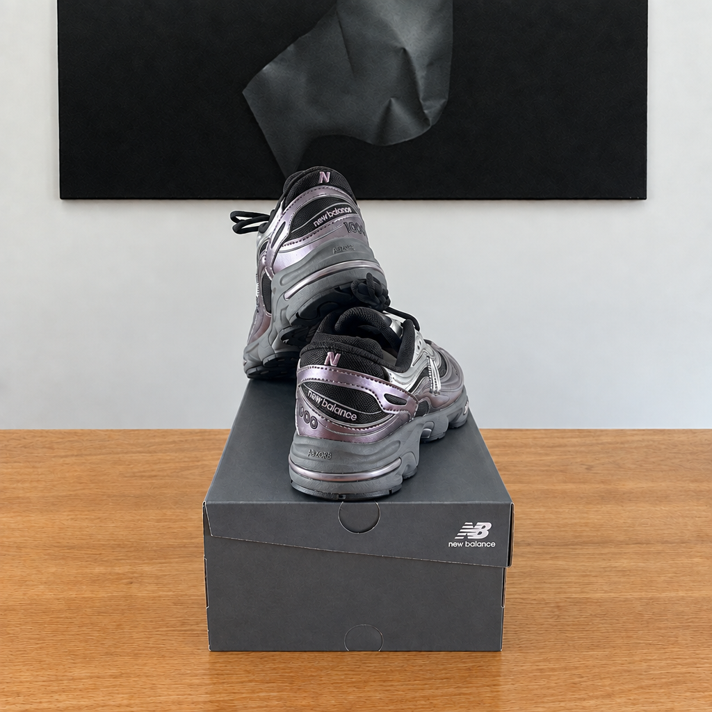 New Balance M1000 EGY : boîte et chaussures centrées sous le tableau noir, sans étiquette blanche à l'arrière
